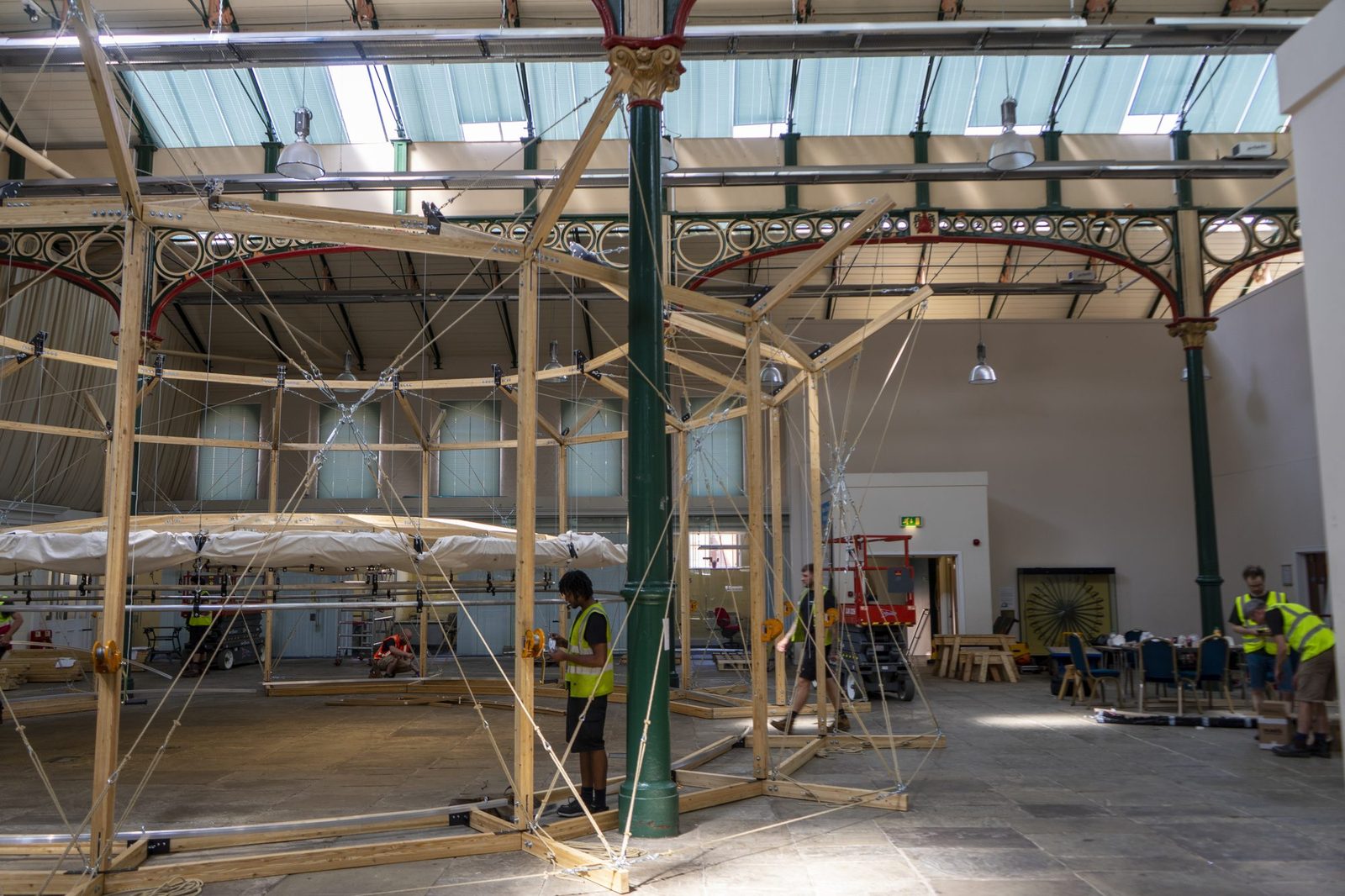 The timber drum during assembly, with people working beside the suspended canopy ring