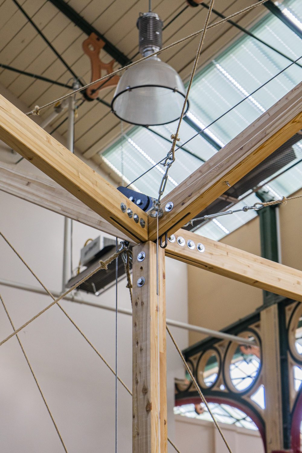 Timber members joined with bolted steel plates at a column head, with rigging above